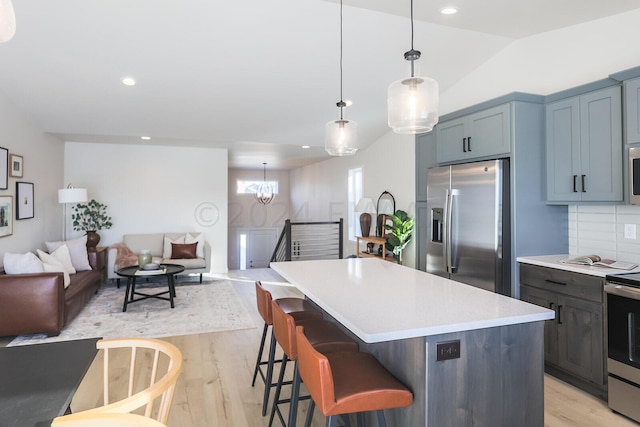 kitchen featuring stainless steel appliances, tasteful backsplash, pendant lighting, and light wood-type flooring