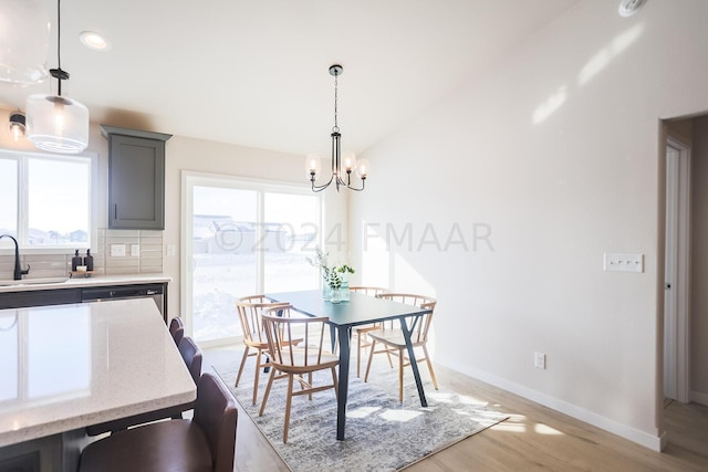 dining space with light hardwood / wood-style flooring, sink, a notable chandelier, and plenty of natural light