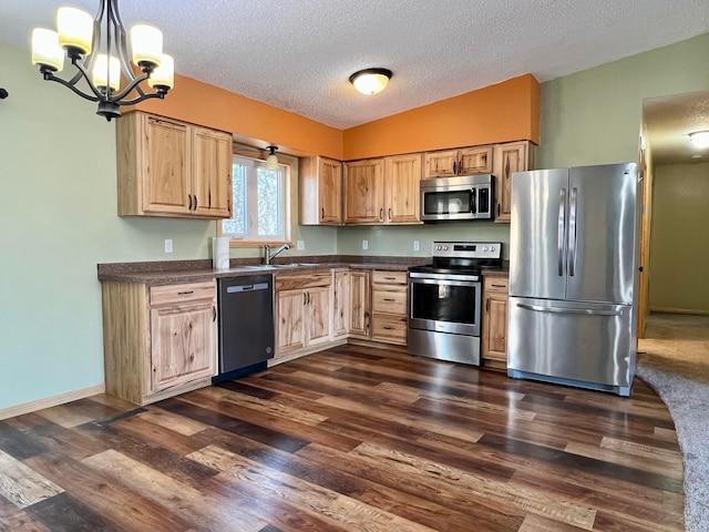 kitchen with dark wood-style flooring, dark countertops, hanging light fixtures, appliances with stainless steel finishes, and light brown cabinets