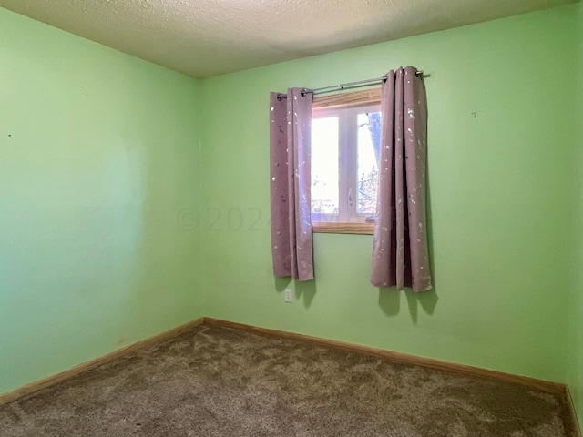 carpeted empty room with baseboards and a textured ceiling