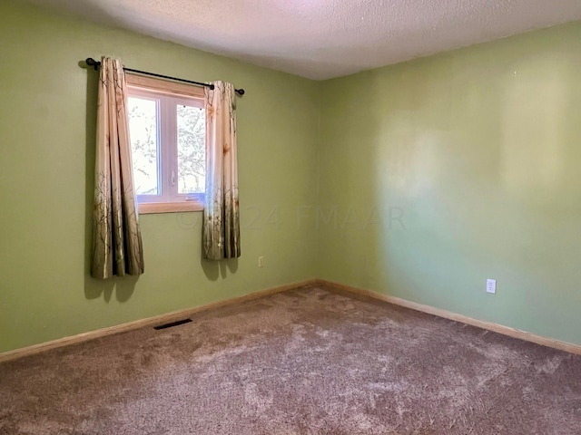 carpeted empty room featuring baseboards, visible vents, and a textured ceiling