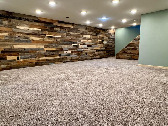 finished basement featuring carpet floors, recessed lighting, wood walls, and stairway