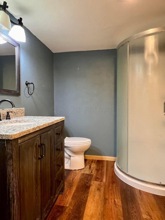 bathroom with toilet, wood finished floors, and vanity