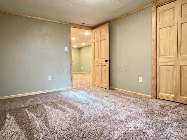 unfurnished bedroom with carpet floors, a textured ceiling, and baseboards