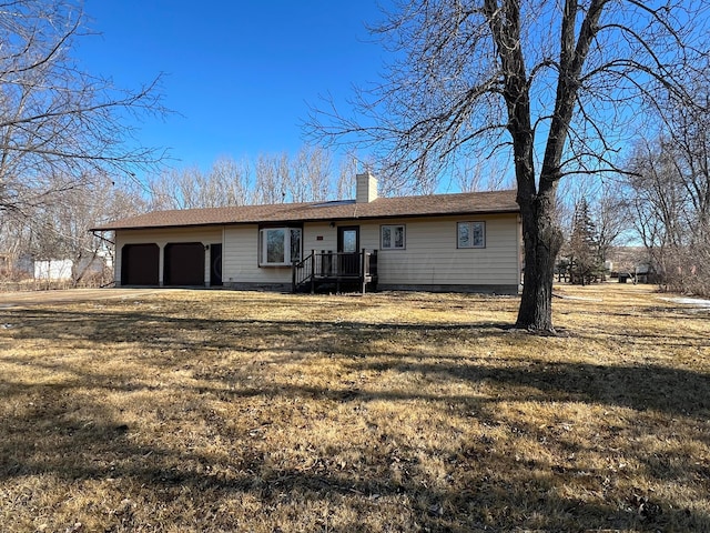 single story home with an attached garage, a chimney, and a front yard