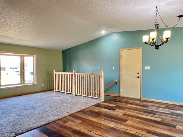 interior space featuring baseboards, lofted ceiling, wood finished floors, a textured ceiling, and a notable chandelier