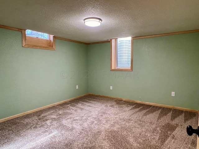 below grade area with carpet floors, a wealth of natural light, ornamental molding, a textured ceiling, and baseboards