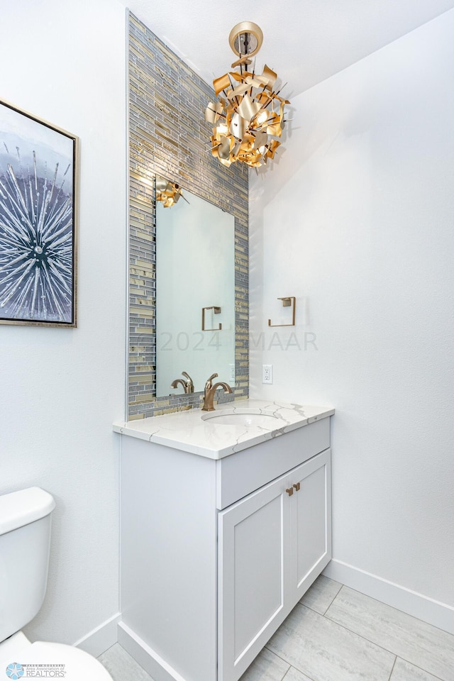 bathroom with tile floors, vanity, toilet, and an inviting chandelier