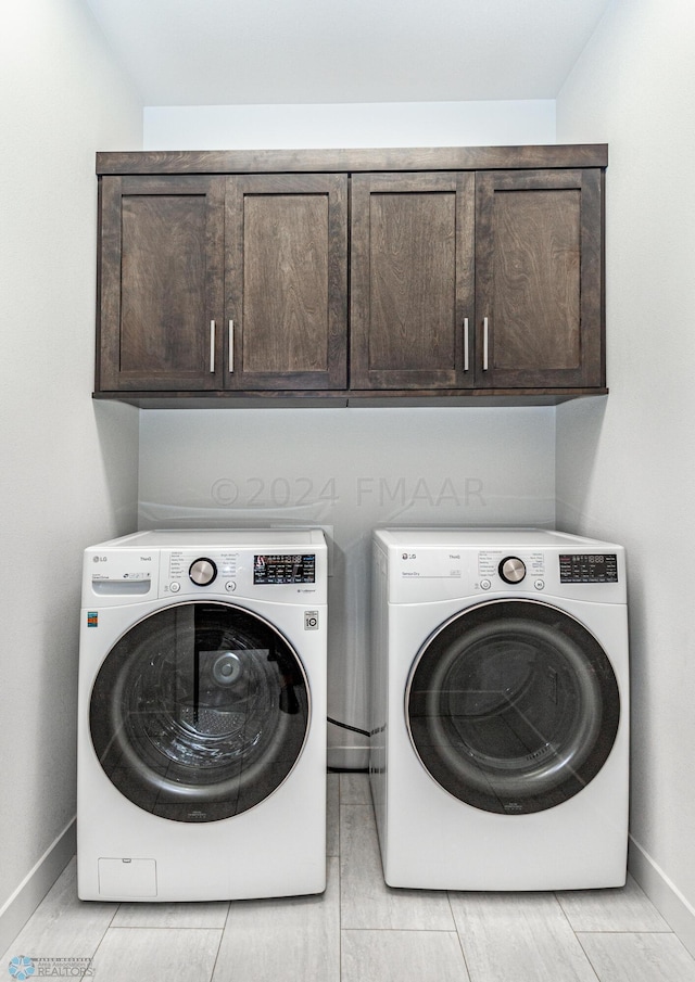 clothes washing area featuring washer and dryer, cabinets, and light tile floors