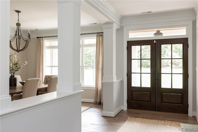 doorway featuring french doors, crown molding, a chandelier, light hardwood / wood-style flooring, and decorative columns