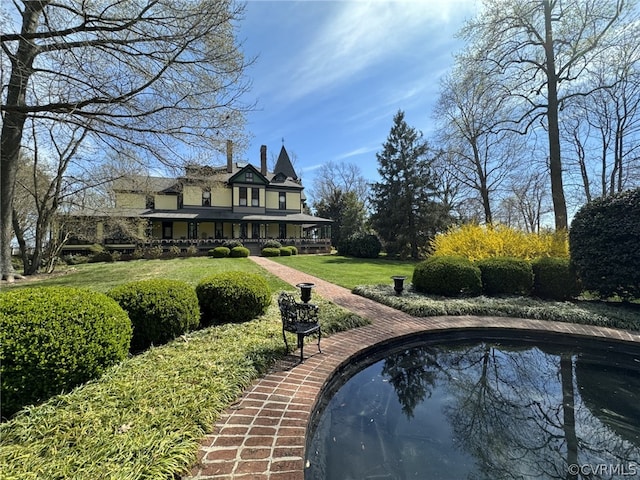 back of house with a swimming pool, a lawn, and brick siding