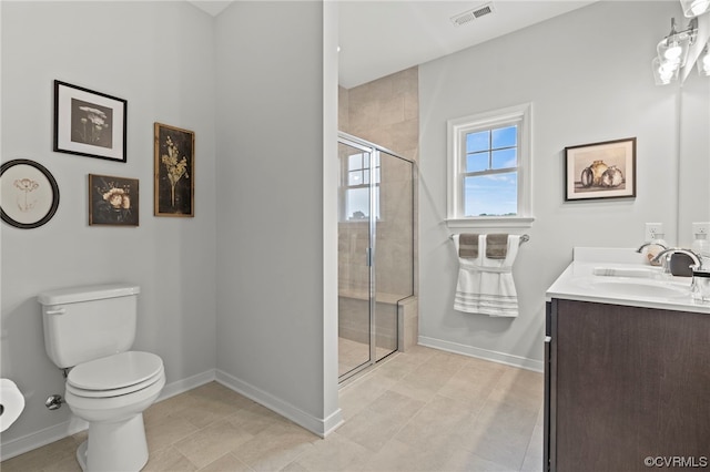 bathroom featuring tile floors, toilet, vanity, and a shower with shower door