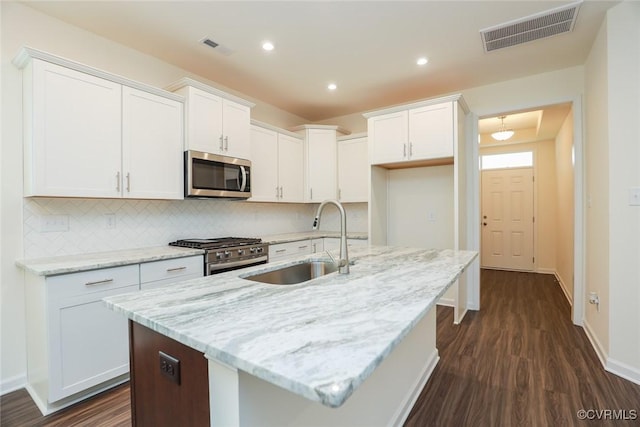 kitchen with white cabinetry, sink, stainless steel appliances, and an island with sink