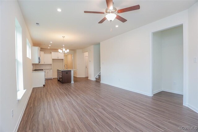 unfurnished living room featuring sink, ceiling fan with notable chandelier, and hardwood / wood-style floors