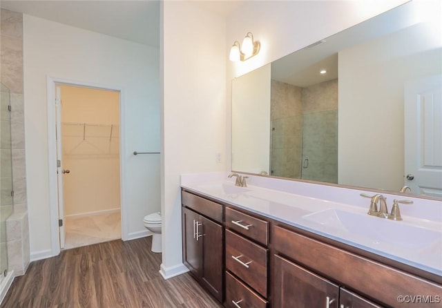 bathroom featuring a shower with door, vanity, hardwood / wood-style flooring, and toilet