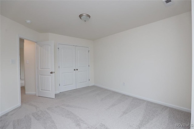 unfurnished bedroom with light colored carpet and a closet