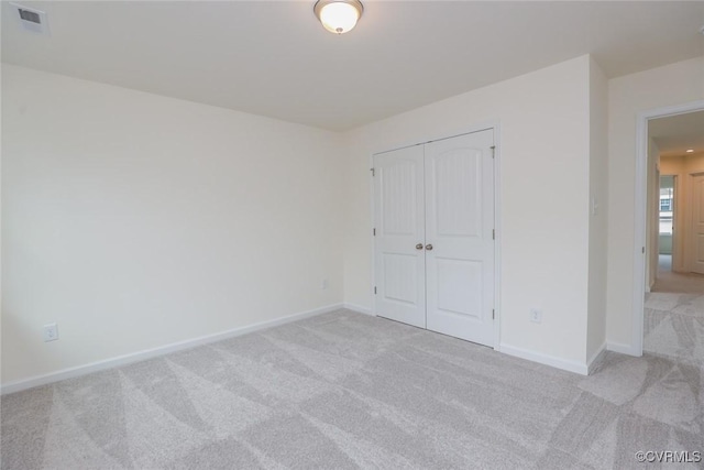 unfurnished bedroom featuring light colored carpet and a closet