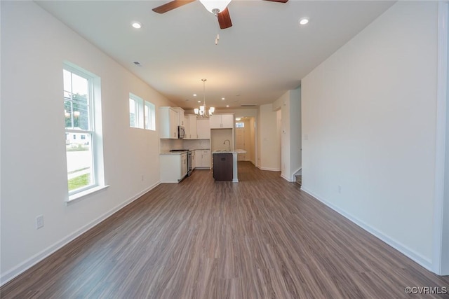 unfurnished living room with sink, ceiling fan with notable chandelier, and dark hardwood / wood-style floors