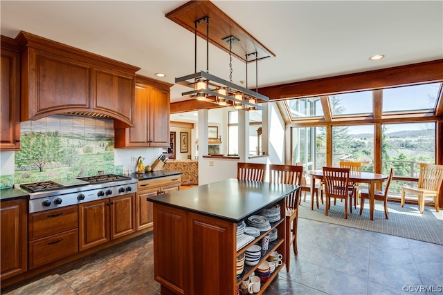 kitchen featuring hanging light fixtures, a kitchen island, stainless steel gas cooktop, and decorative backsplash