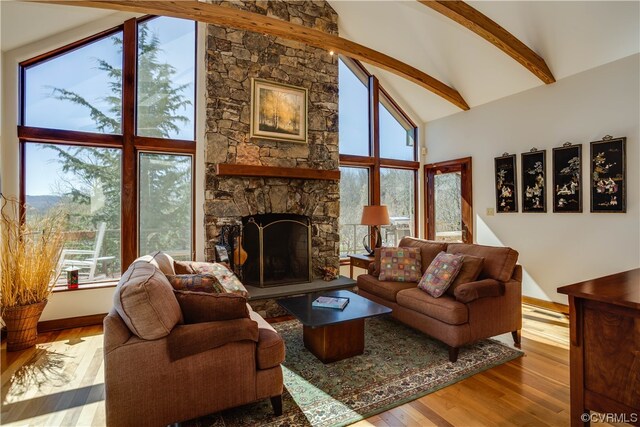 living room with beamed ceiling, high vaulted ceiling, a fireplace, and light hardwood / wood-style floors