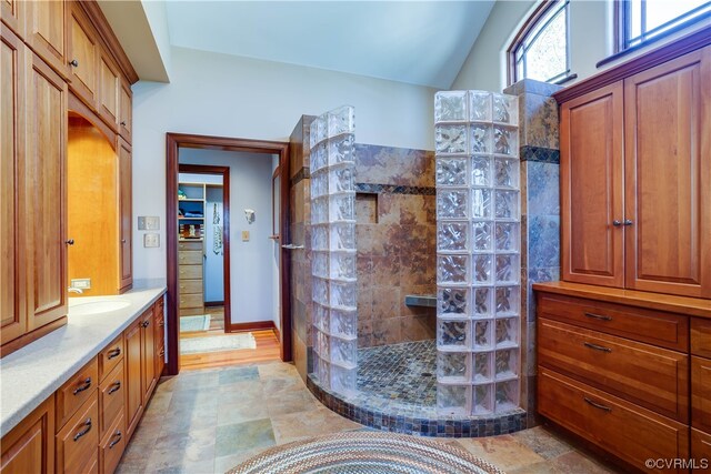 bathroom with vanity, vaulted ceiling, and tiled shower