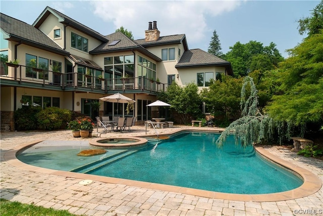 back of house featuring a swimming pool with hot tub and a patio