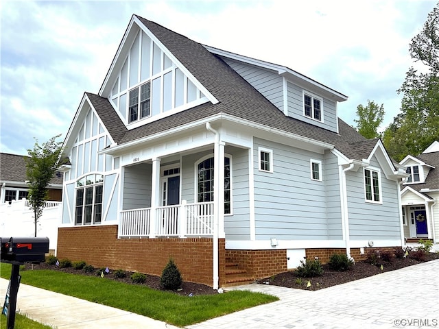 view of side of home with crawl space, board and batten siding, a porch, and a shingled roof