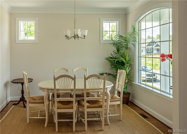 dining space featuring an inviting chandelier, a healthy amount of sunlight, wood-type flooring, and ornamental molding