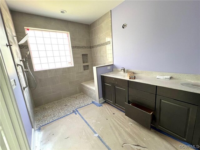 bathroom with tiled shower and double sink vanity