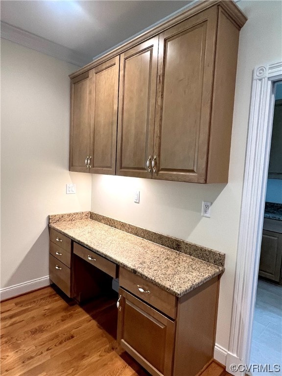 kitchen featuring light stone counters, built in desk, and hardwood / wood-style floors