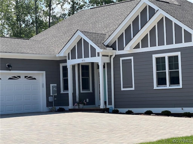 view of front of property featuring an attached garage, a shingled roof, decorative driveway, and board and batten siding