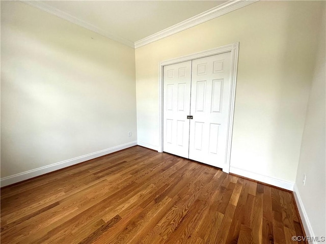 unfurnished bedroom with dark wood finished floors, crown molding, baseboards, and a closet