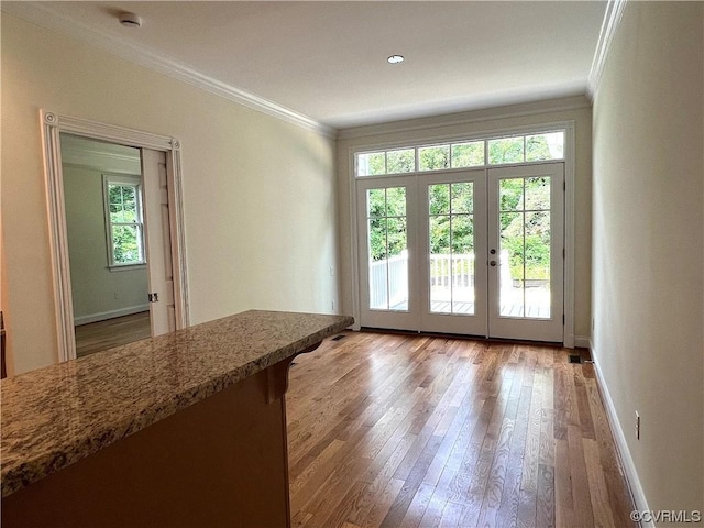 doorway to outside with a wealth of natural light, crown molding, and hardwood / wood-style flooring