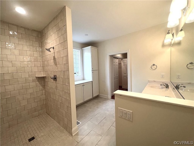 full bath featuring double vanity, tiled shower, and a sink