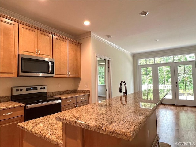 kitchen with ornamental molding, hardwood / wood-style floors, recessed lighting, stainless steel appliances, and light stone countertops