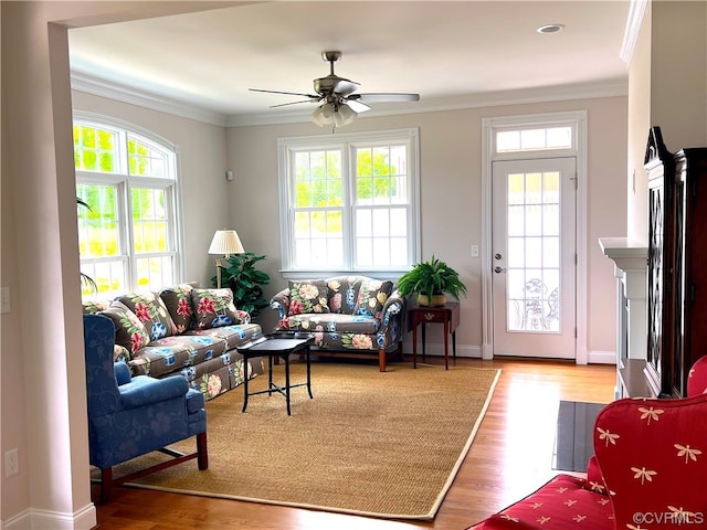 living room with ceiling fan, wood finished floors, baseboards, and ornamental molding