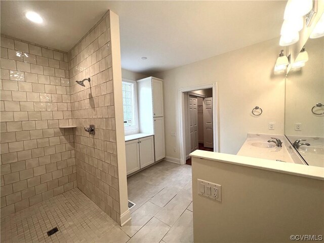 bathroom with double vanity, a tile shower, and a sink