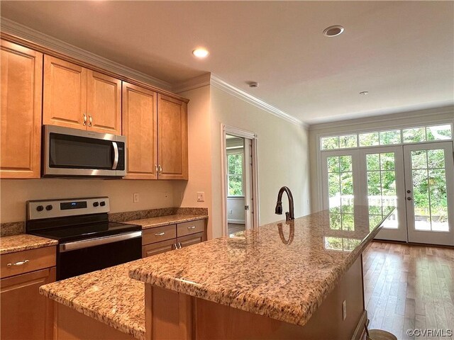 kitchen featuring crown molding, light stone countertops, recessed lighting, appliances with stainless steel finishes, and hardwood / wood-style flooring