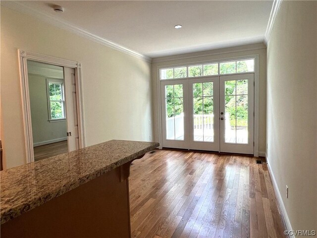 doorway to outside featuring a wealth of natural light, wood finished floors, and ornamental molding