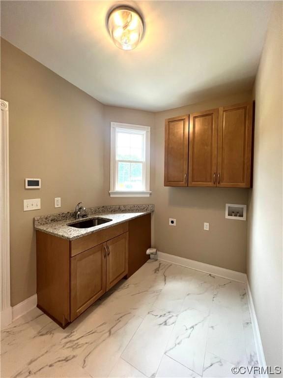 kitchen featuring a sink, baseboards, brown cabinets, and marble finish floor