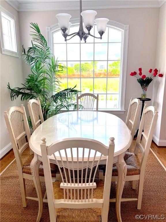 dining space with an inviting chandelier, baseboards, light wood finished floors, and ornamental molding