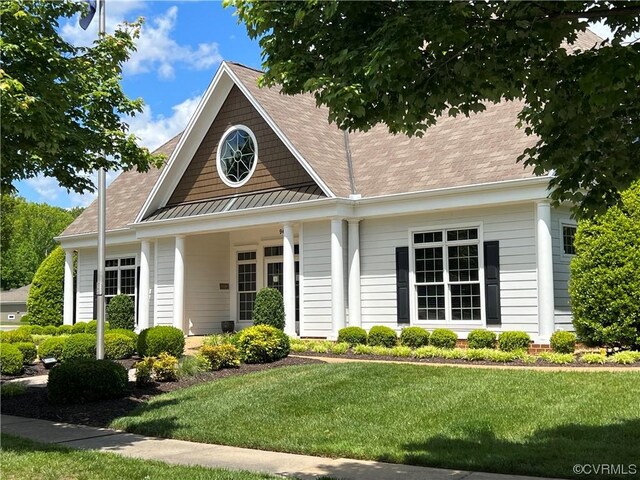 view of front facade featuring a standing seam roof, metal roof, and a front yard