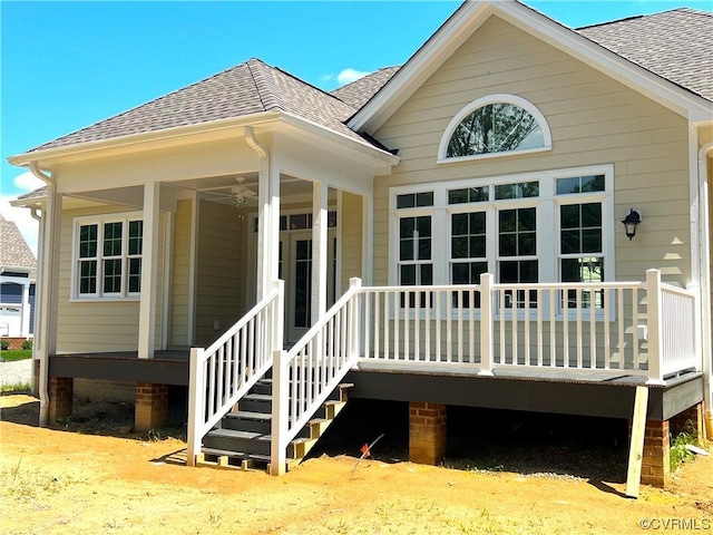 entrance to property with a porch and roof with shingles