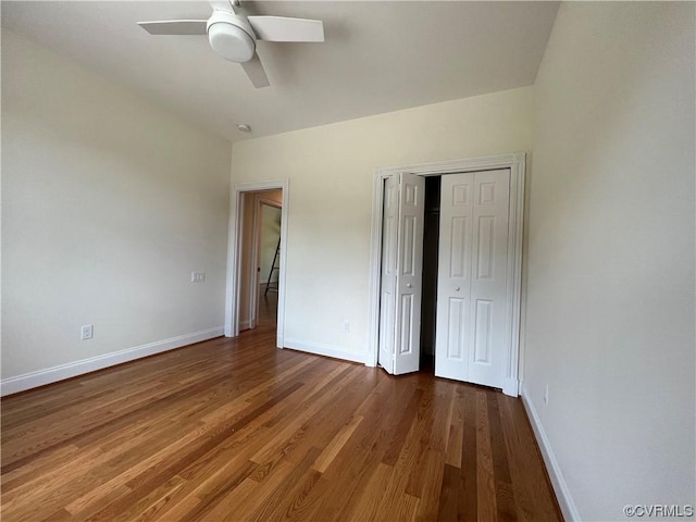 unfurnished bedroom featuring a closet, baseboards, wood finished floors, and a ceiling fan