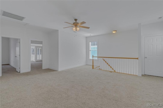 unfurnished room featuring a ceiling fan, light colored carpet, visible vents, and baseboards