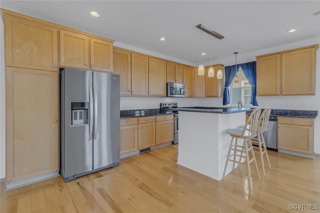 kitchen featuring a breakfast bar, a center island, hanging light fixtures, stainless steel appliances, and light wood-type flooring