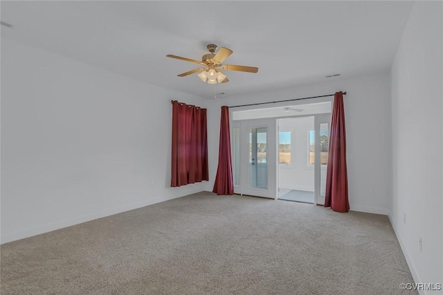 spare room featuring light carpet, ceiling fan, and baseboards