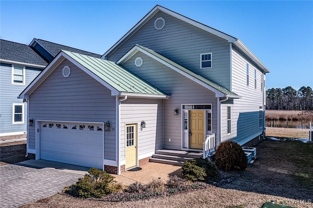 traditional-style house featuring a garage, driveway, a standing seam roof, and metal roof