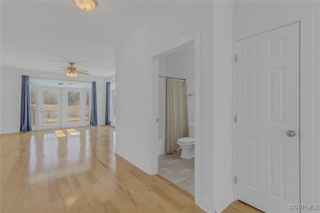 corridor featuring baseboards and light wood-style floors