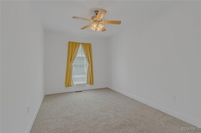 carpeted spare room with ceiling fan and baseboards